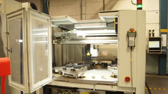 En industriell CNC-maskin med öppet lock som visar de inre komponenterna och en kontrollpanel åt sidan.