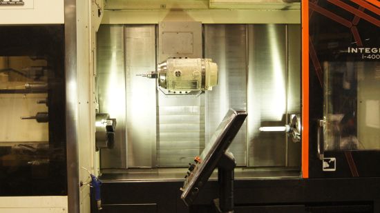 Närbild av ett CNC-bearbetningscenter med en kontrollpanel och en metallkomponent monterad inuti, redo för precisionstillverkning.